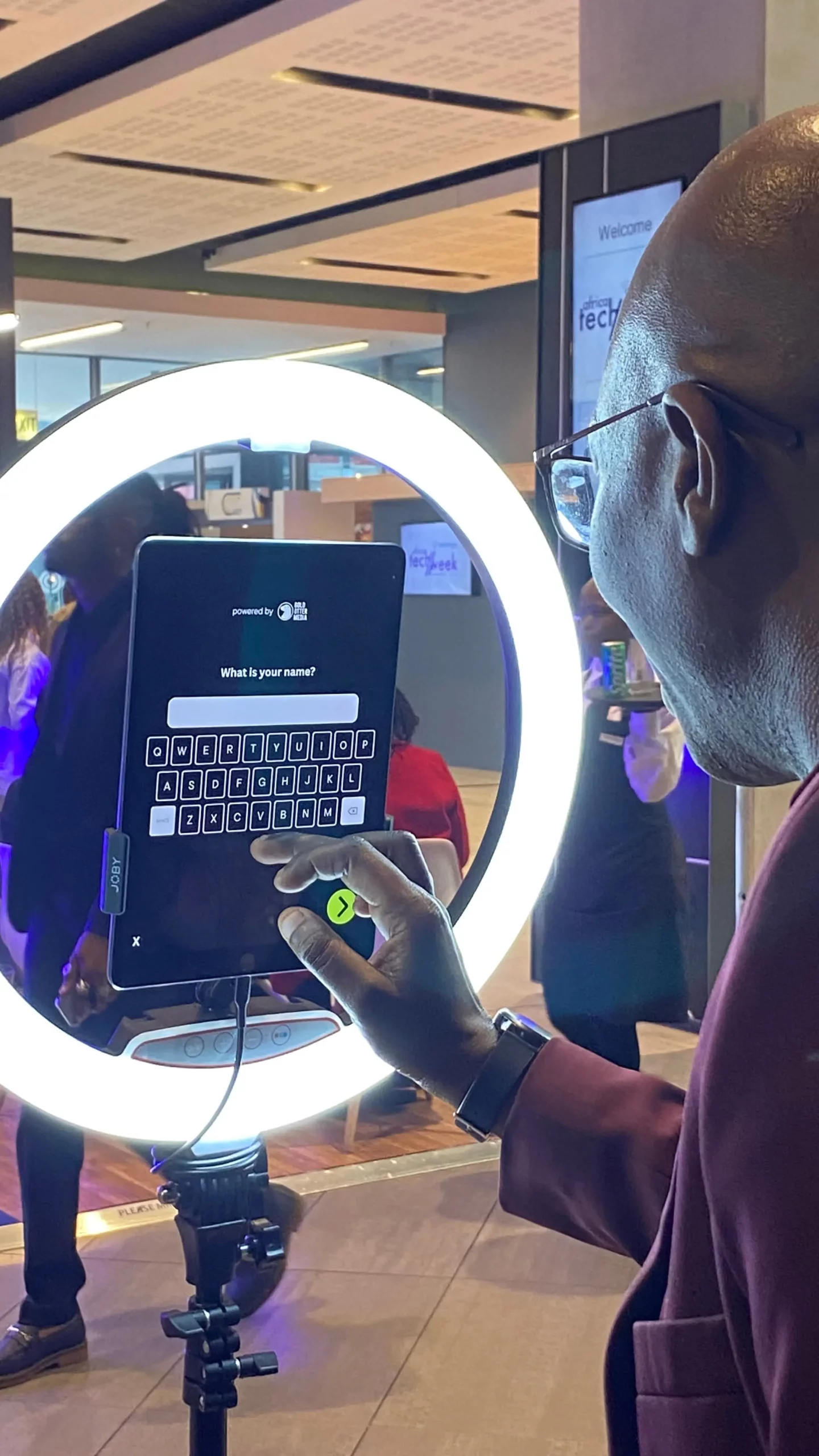 A guest enters their name on a tablet framed by a ring light at a lead capture station at the Centrury City Convention Centre..