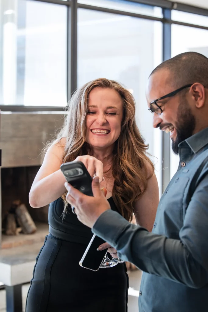 A smiling woman and man view a phone after receiving AI digital portrait.